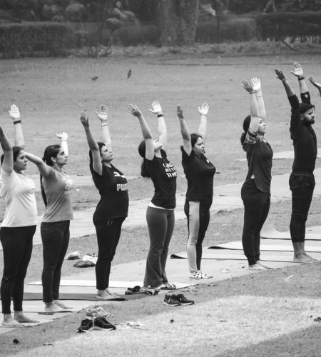 About A group of people practicing yoga outdoors, captured in a black and white photograph.